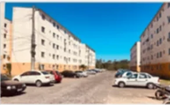 Foto de vistoria: dois blocos residenciais vistos do estacionamento, em dia de sol